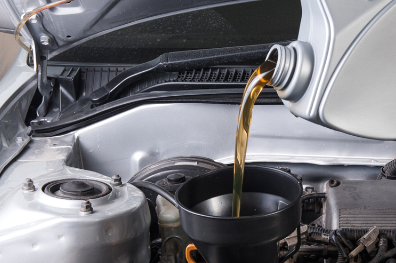 A person changing oil with tools laid out for a DIY oil change process