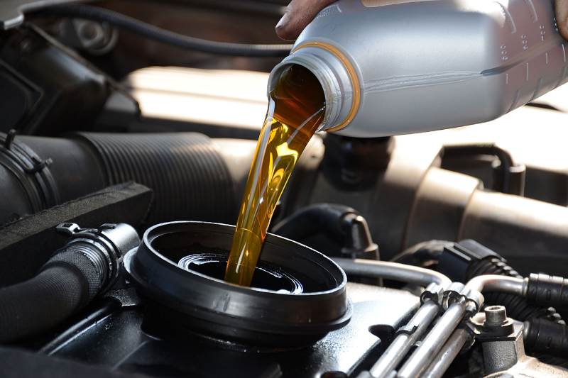 A person changing oil with tools laid out for a DIY oil change process